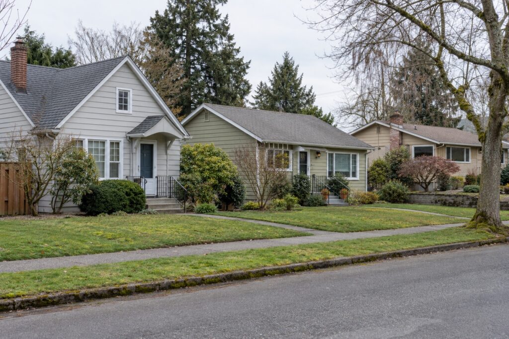 Three neighboring detached homes with different facades and mature landscaping.