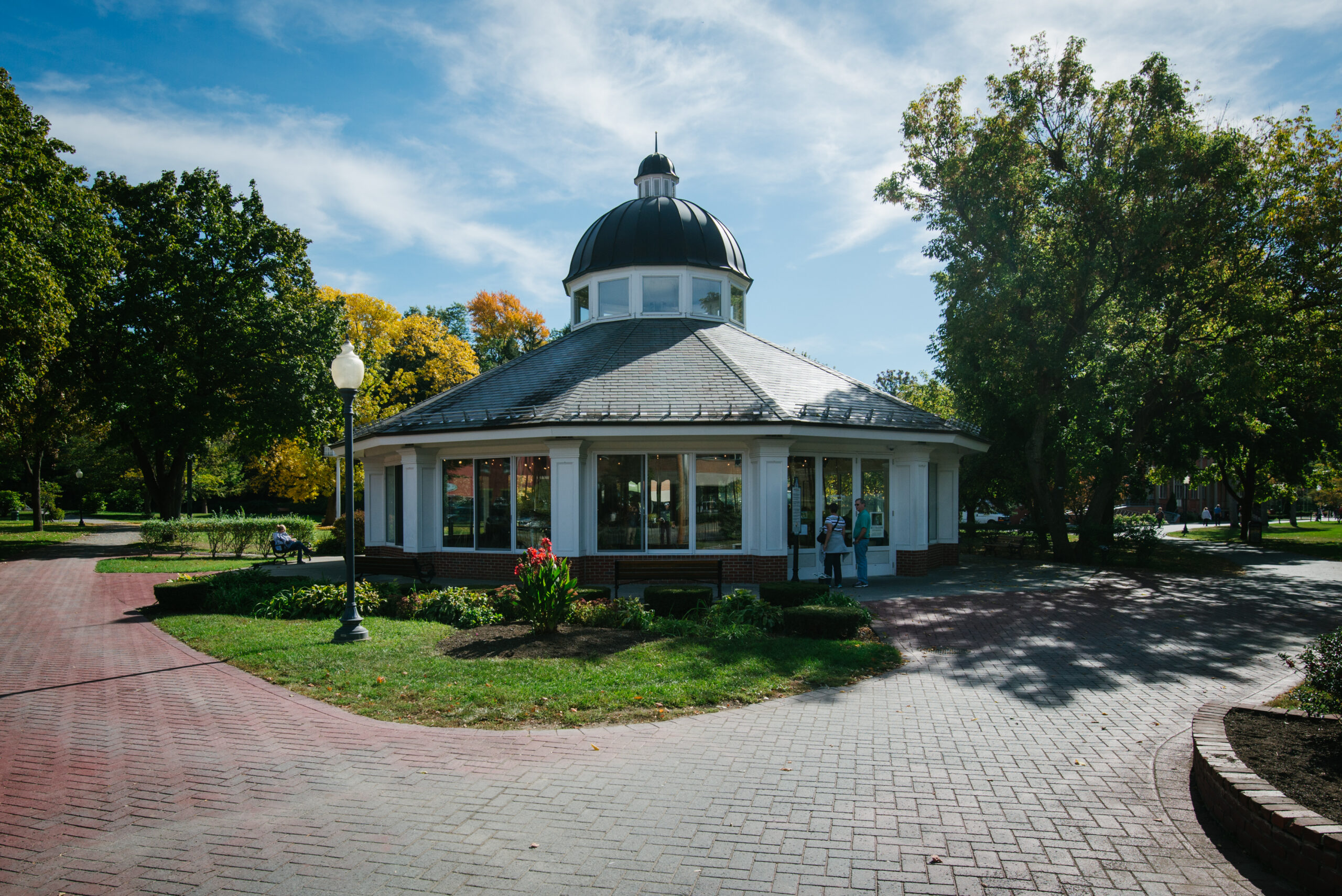 Congress Park carousel pavilion framed by trees and brick paths in Saratoga Springs, New York.