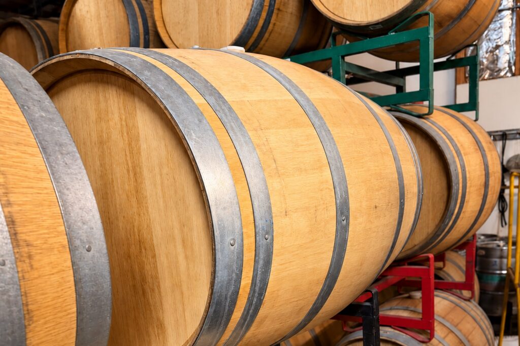 Oak wine barrels stacked on metal racks in a cellar.